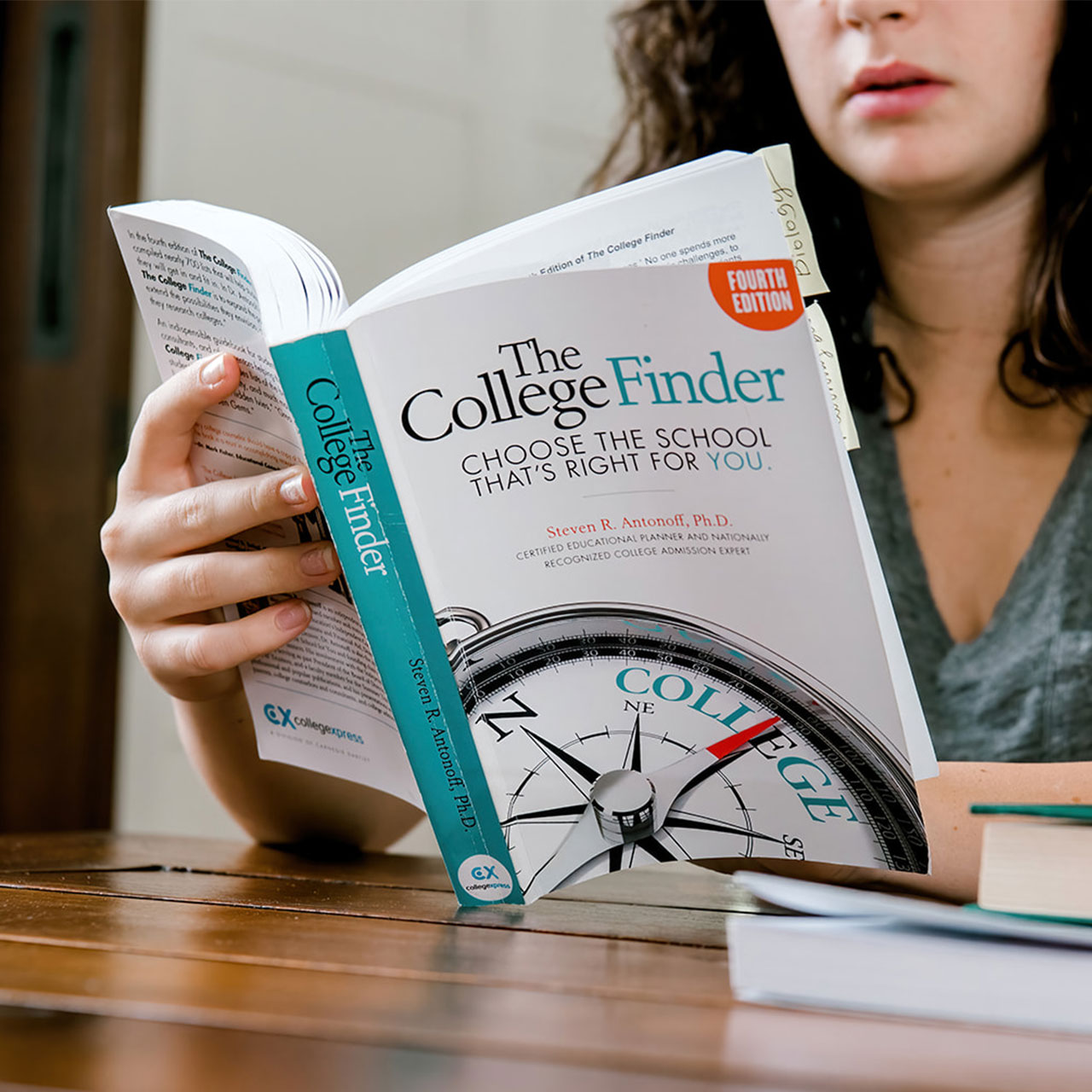 Student Reviewing a Book called, "The College Finder"
